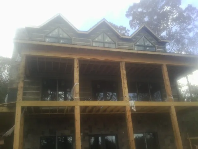 Dormers and porch framing on a large log home under construction — Roof Coating work by our crew in Osage